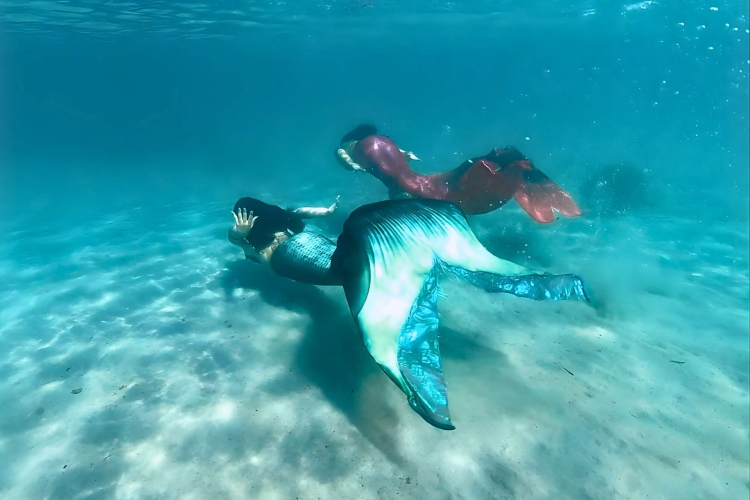 Deux personnes en costume de sirène nagent dans la mer de Cagliari