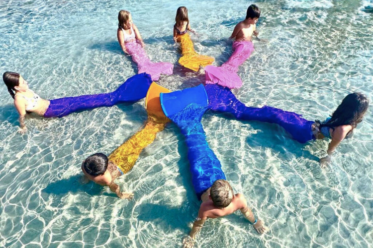 Enfants avec des nageoires de sirène dans l'eau sur une plage de Poetto à Cagliari