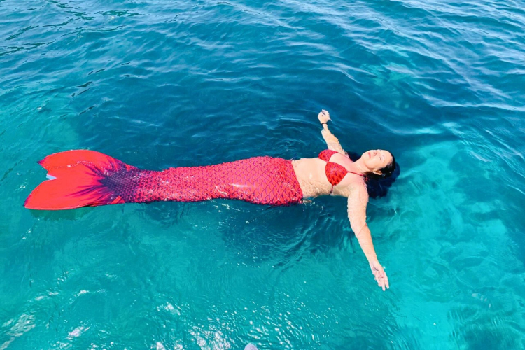 Une personne à la queue de sirène rouge nage dans les eaux cristallines de la mer.
