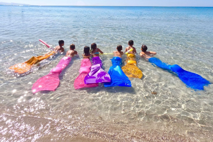 Enfants avec des nageoires de sirène dans l'eau sur une plage de Poetto à Cagliari