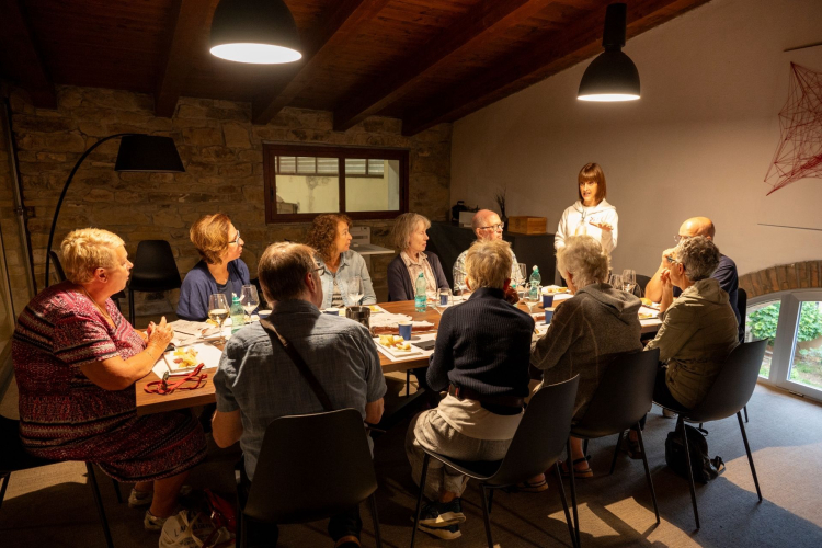 Group of people in a winery with a guide explaining during wine tasting