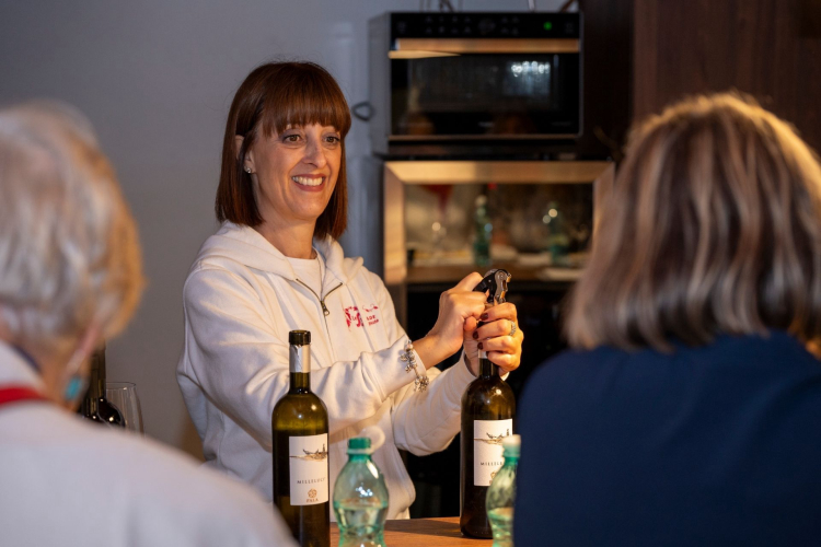 The guide opens a bottle of wine for tasting in a winery in Serdiana