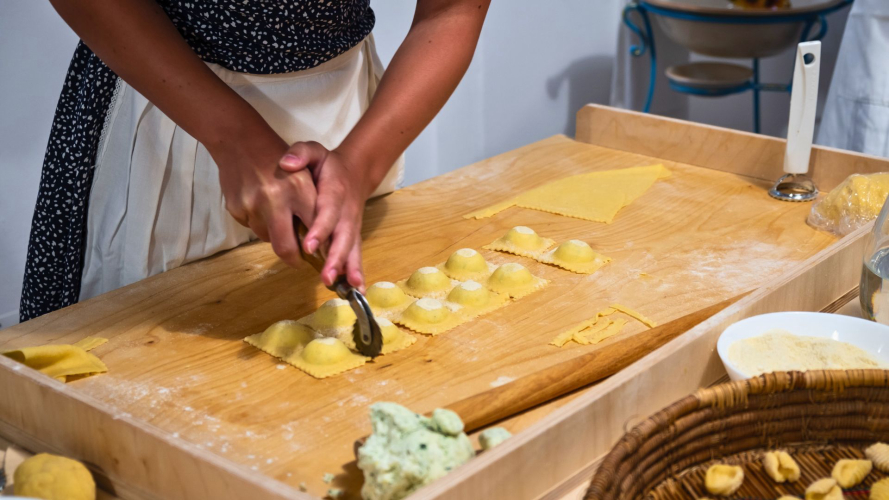Una persona sta preparando ravioli tradizionali su un tagliere di legno