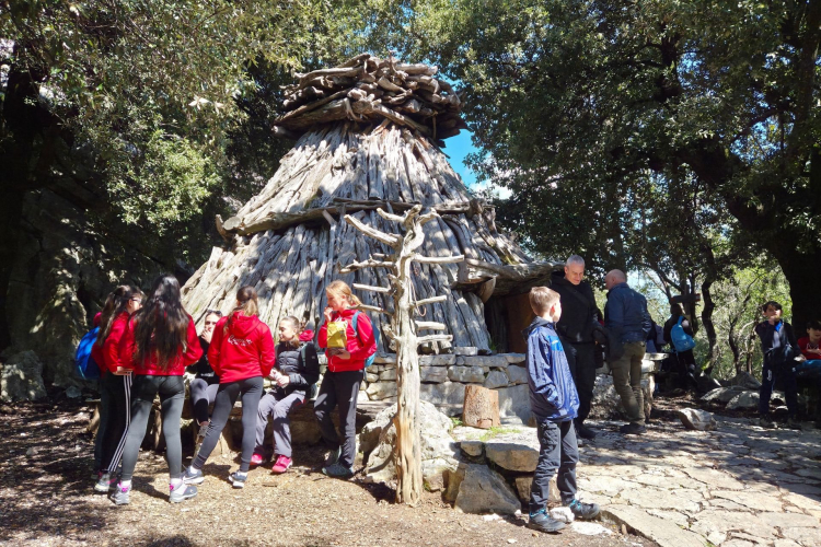 Un gruppo di persone osserva un tipico cuile, l'antica casa dei pastori sardi