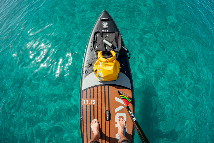 Un homme debout sur une planche à pagaie, dans des eaux turquoises