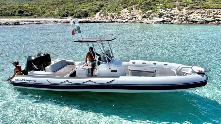 Una barca con un uomo e una donna in acqua cristallina vicino a una costa rocciosa