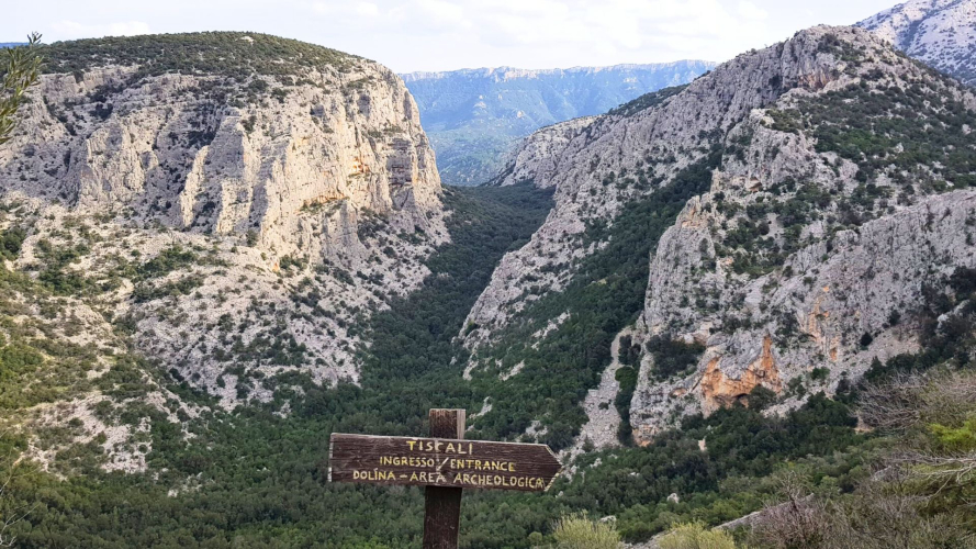 Descripción general de un sumidero con un letrero que indica la entrada al pueblo nurágico de Tiscali