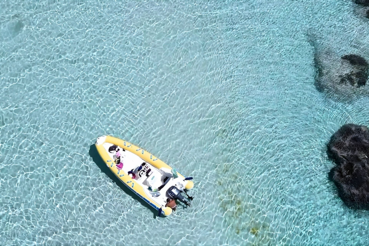 Raft in crystal clear water with a person snorkeling in La Pelosa