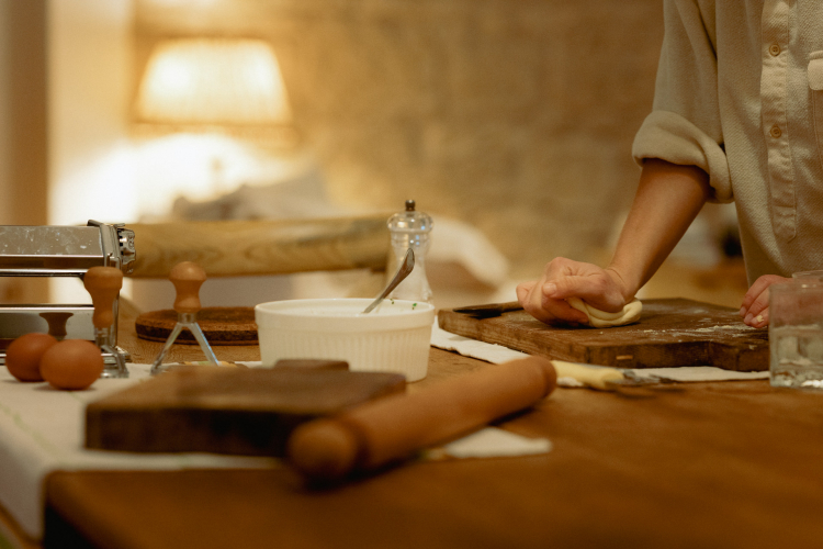 Una persona in cucina, con un tavolo pieno di ingredienti freschi