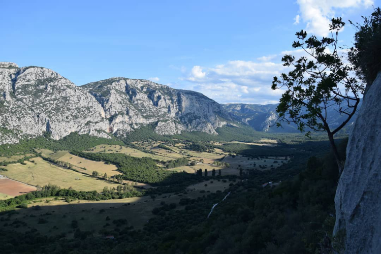 Vue panoramique sur une vallée avec des montagnes, des bois et un village nuragique au sommet d'une montagne