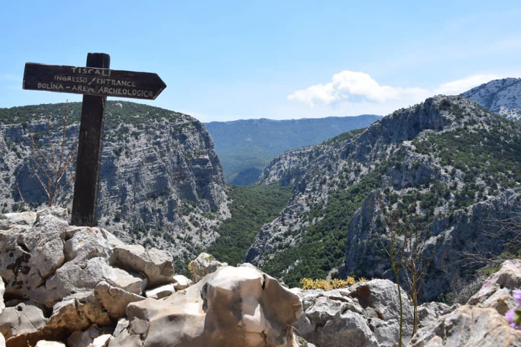 Panneau en bois indiquant l'entrée d'une zone archéologique avec vue sur les montagnes et les vallées