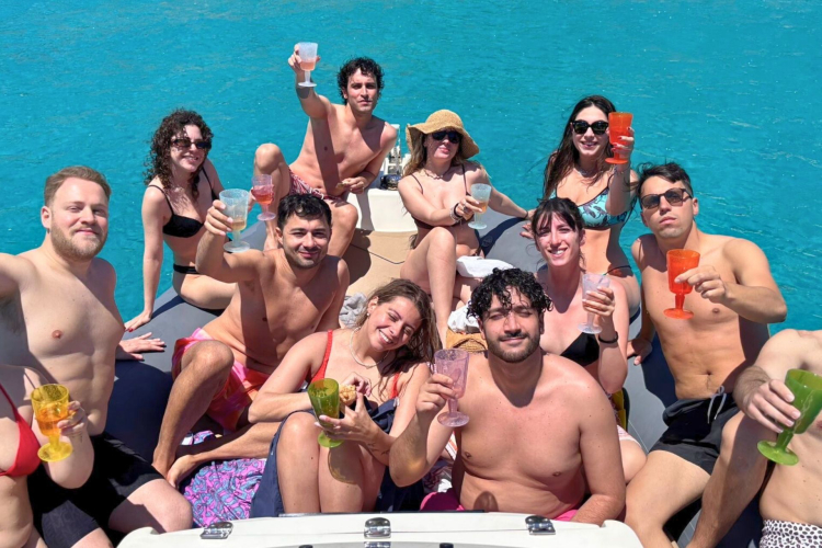 Gruppe von Menschen in einem Beiboot, lächeln und tosten im smaragdgrünen Meer von La Maddalena