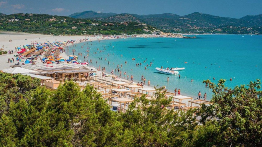 Un gruppo di persone gode del sole su una spiaggia con acqua cristallina a Punta Molentis