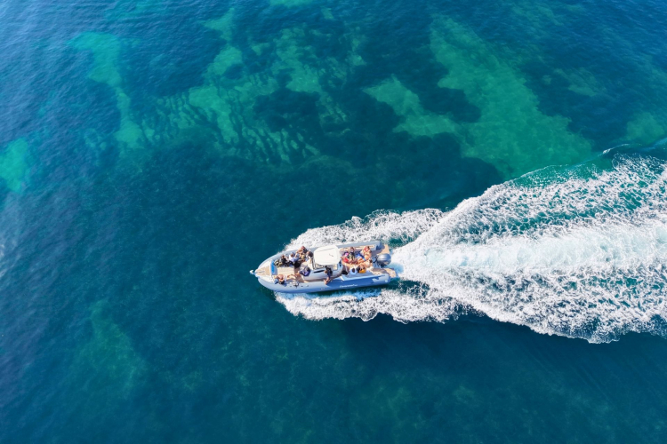 Un gommone con persone a bordo che naviga lungo una costa di Cagliari