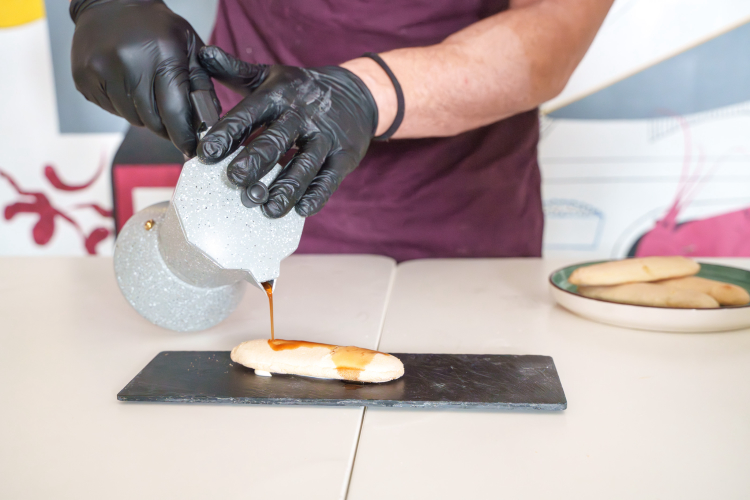 The ladyfinger is soaked in coffee, Tiramisù is prepared during the cooking class in Olbia