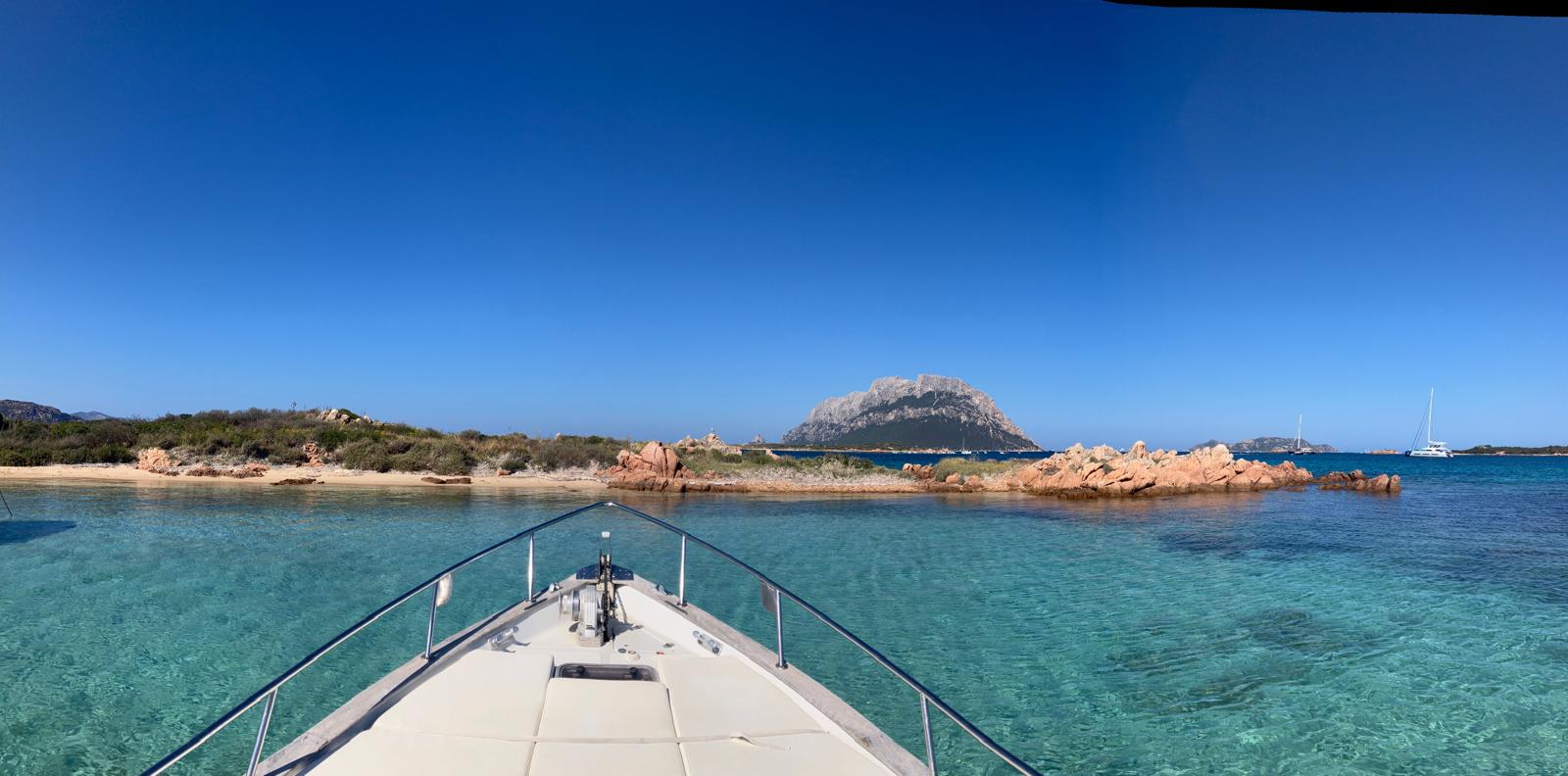 Gozzo that sails along the northeastern coast of the Tavolara Marine Protected Area, with the Island of Tavolara