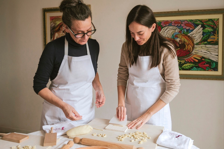 Un cocinero enseña a un participante a trabajar pasta durante un taller privado en Cagliari