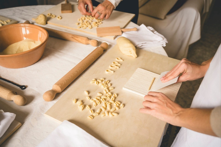 Dos personas en un taller privado de pasta sarda en Cagliari, con ingredientes y utensilios de cocina sobre una mesa
