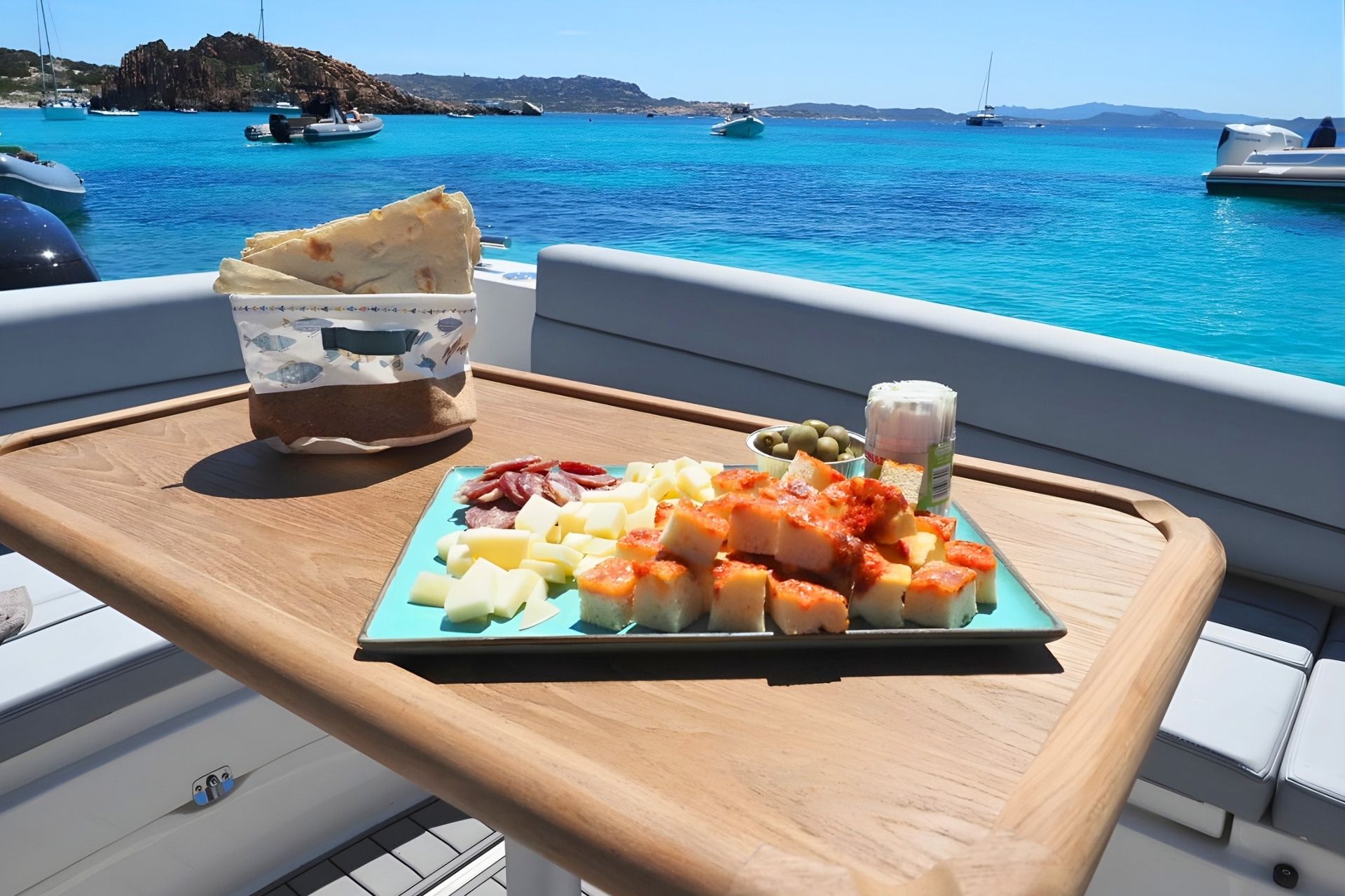 Aperitif an Bord des Jollens mit Blick auf das türkisfarbene Meer von La Maddalena