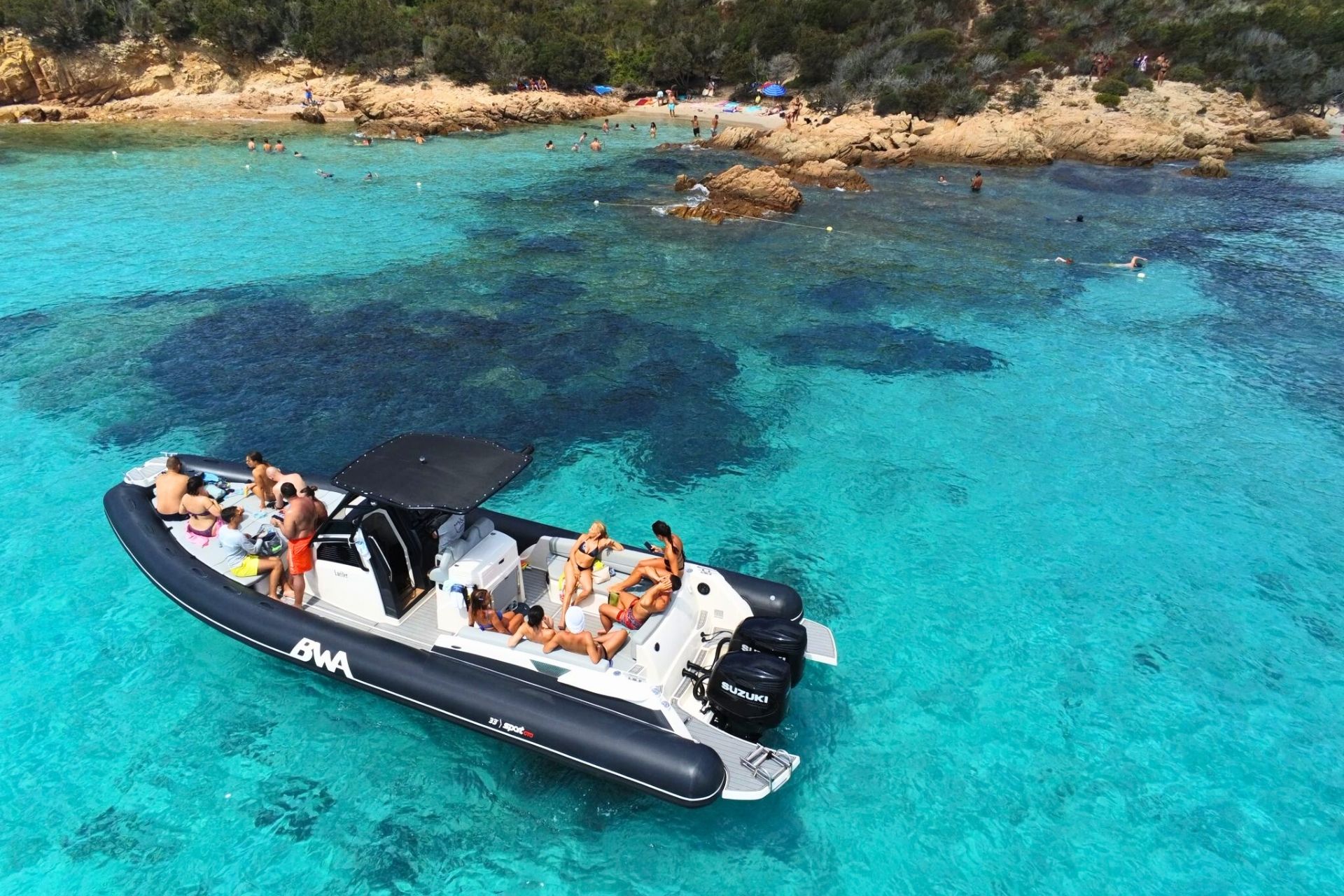 Eine Gruppe von Menschen an Bord eines Schlauchbootes im kristallklaren Wasser des La Maddalena-Archipels, die wilde Inseln und versteckte Buchten besuchen.