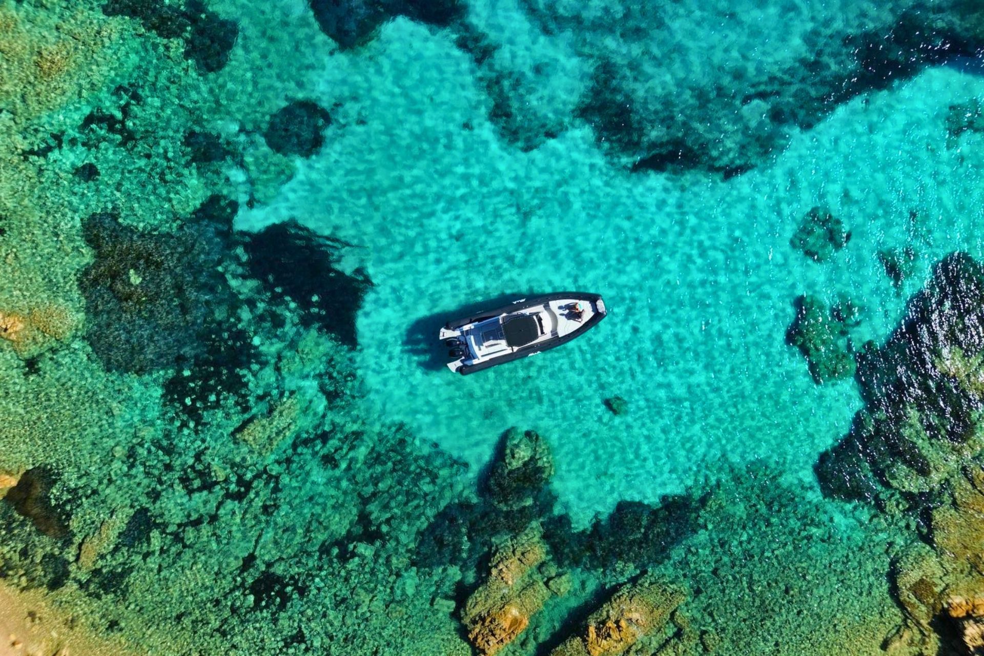 Das Beiboot parkt im kristallklaren Wasser des La Maddalena-Archipels mit sichtbaren Stränden und durchsichtigen Kulissen.