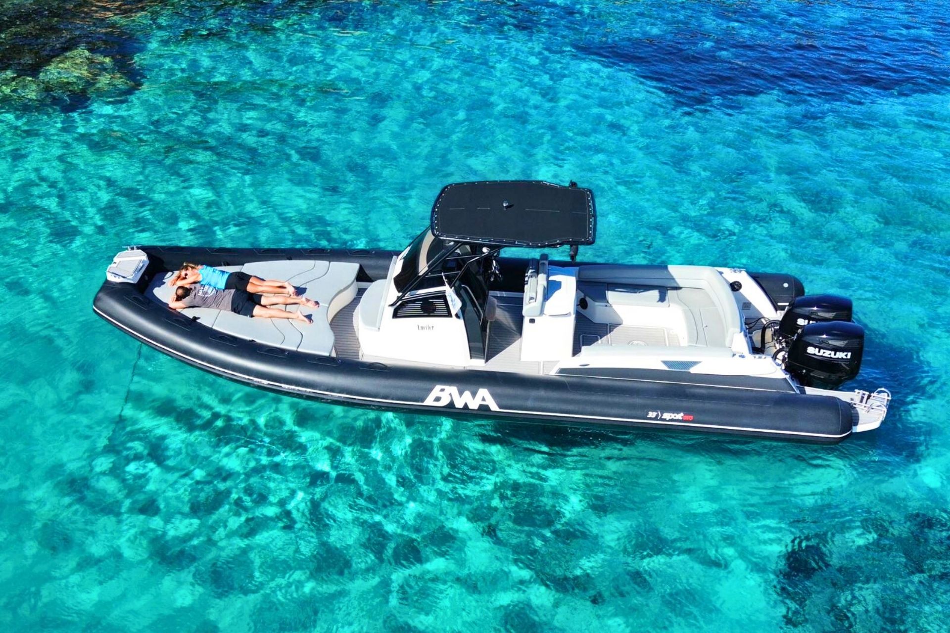Zwei Personen entspannen sich auf einem Beiboot in kristallklarem Wasser.