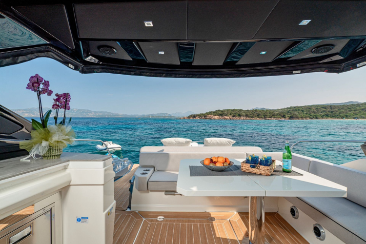 Meerblick auf eine Yacht mit Tisch, Obst und Blumen, mit Inseln im Hintergrund.