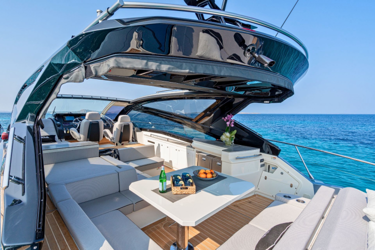 Innenraum einer luxuriösen Privatyacht mit Tisch, Stühlen und Meerblick, bereit für einen Tag voller Freizeit und Entspannung.