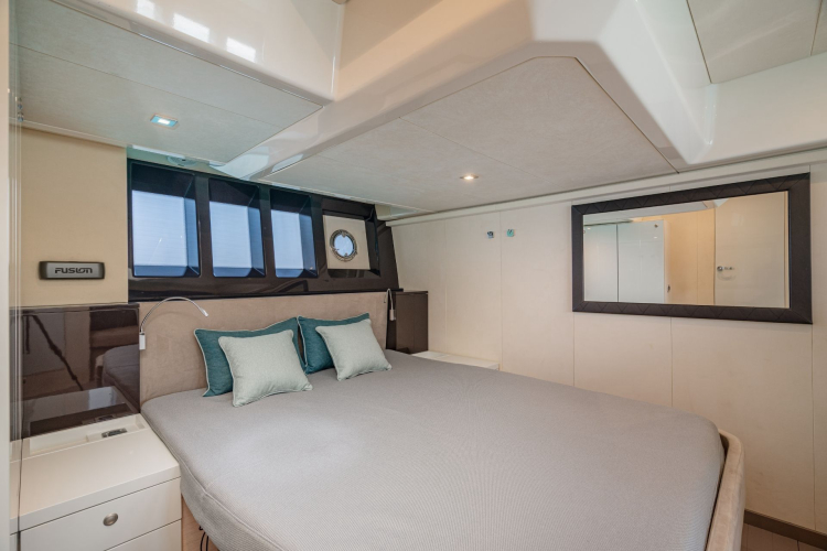 Bild eines Schlafzimmers auf einer privaten Yacht mit Panoramafenstern und einem bequemen Bett, ideal für eine luxuriöse Tagesmiete auf Sardinien.
