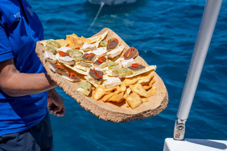 Lo staff serve un aperitivo di prodotti sardi a bordo del tour in monomarano