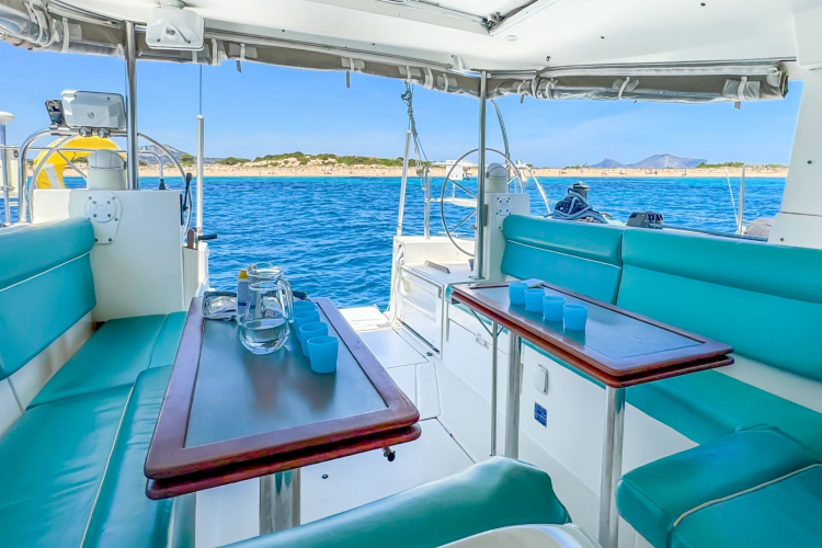 Interno di un monomarano con tavolini e sedili imbottiti sotto il tendalino durante una sosta