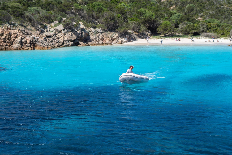 Une personne à bord d'un canot se déplace dans une eau turquoise avec une île en arrière-plan.