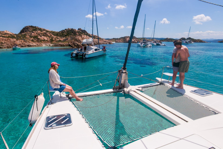 Un groupe de personnes sur un catamaran dans une baie avec une mer turquoise et des îles en arrière-plan