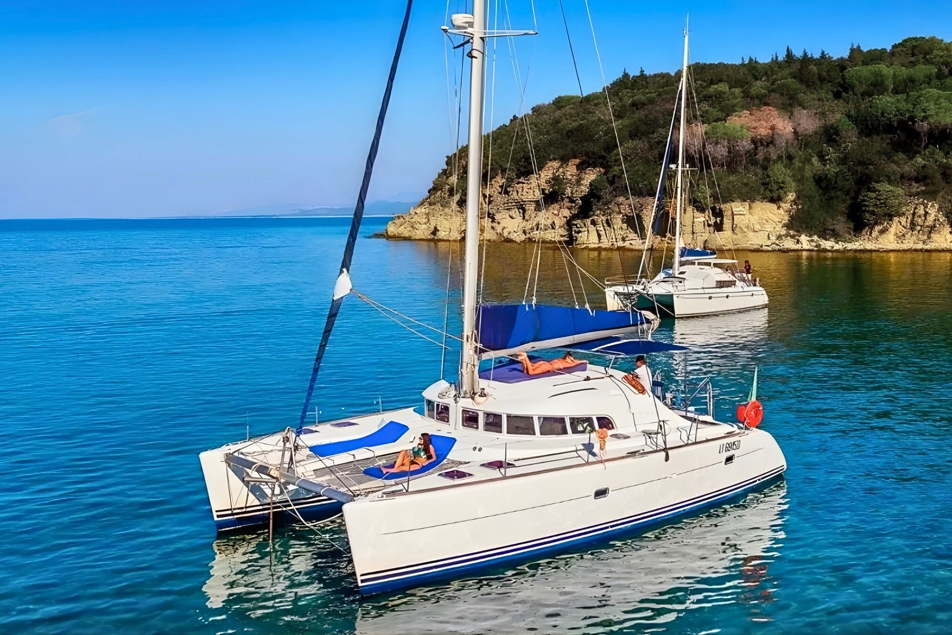 Catamarán con personas a bordo en aguas cristalinas con islas al fondo
