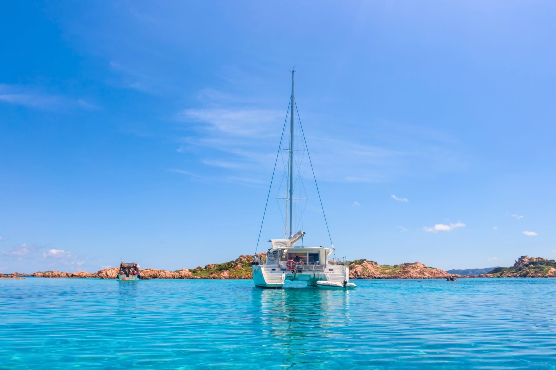 Navegación en catamarán en aguas cristalinas con islas al fondo