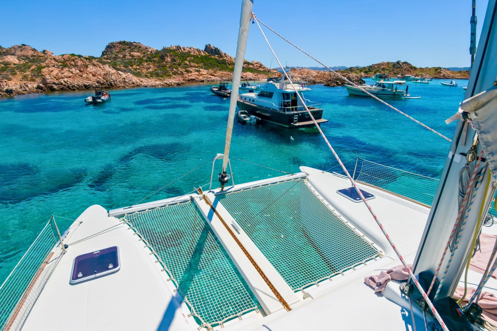 Catamaranes y otros barcos amarrados en aguas cristalinas con islas al fondo