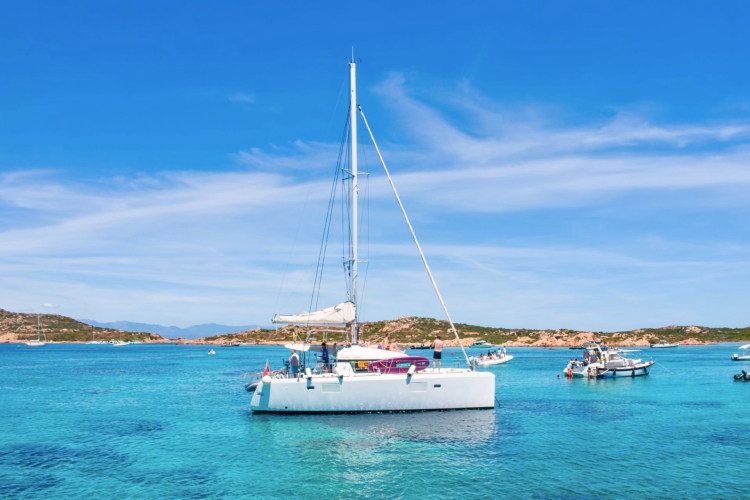 Image of a catamaran in a bay with white beaches and crystal clear waters.