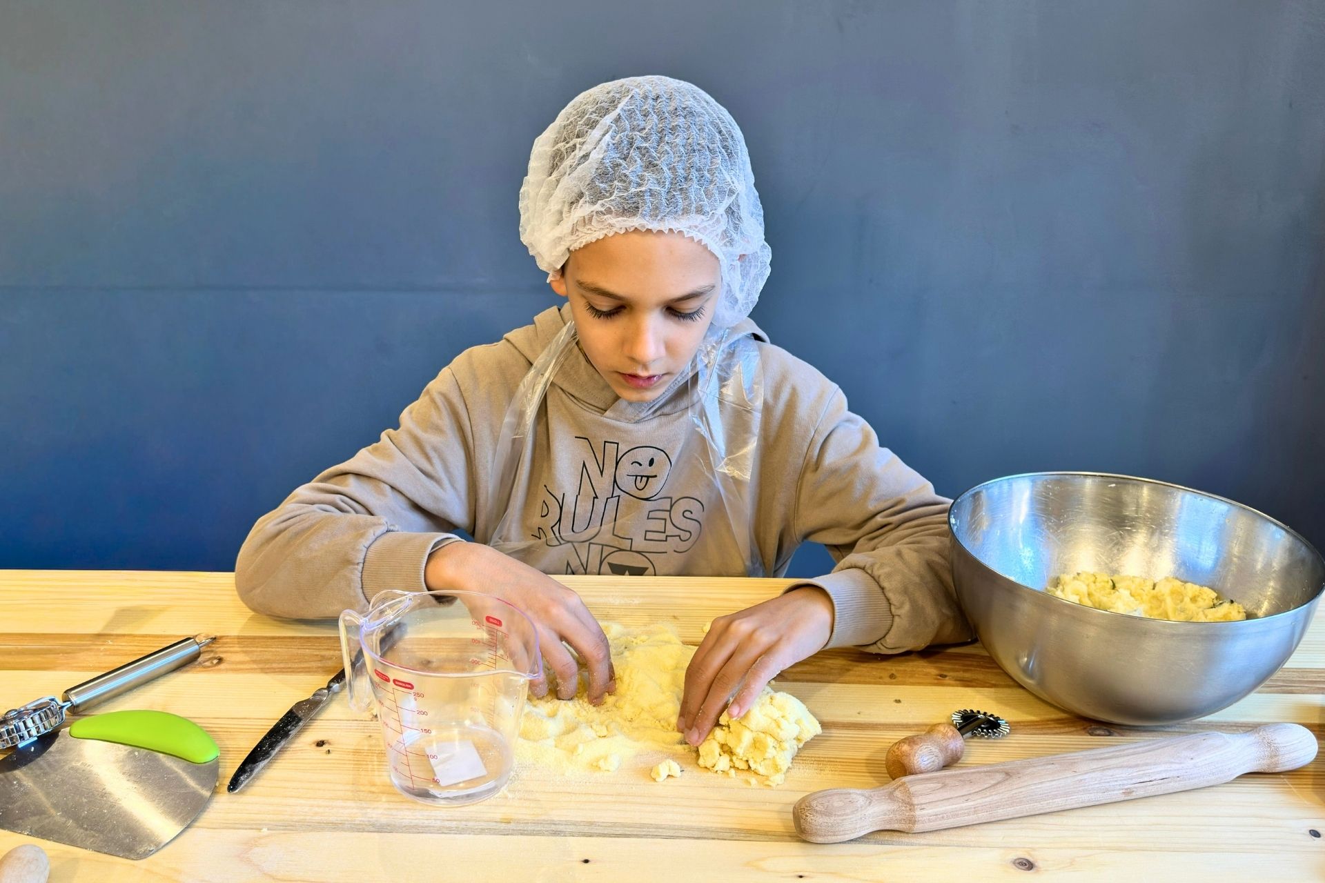 Un giovane partecipa a un laboratorio di pasta fresca ad Alghero, impastando e preparando piatti tipici sardi.