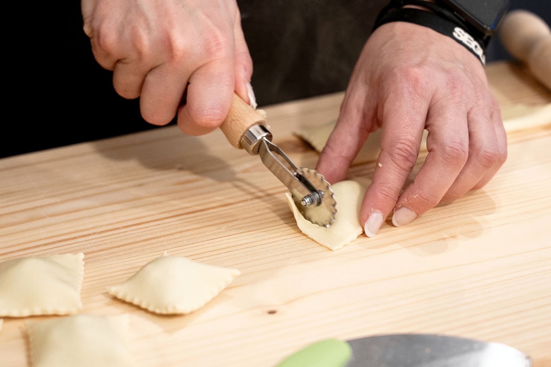 Una persona sta utilizzando un tagliapasta per creare ravioli in un laboratorio artigianale all'interno di una panetteria.