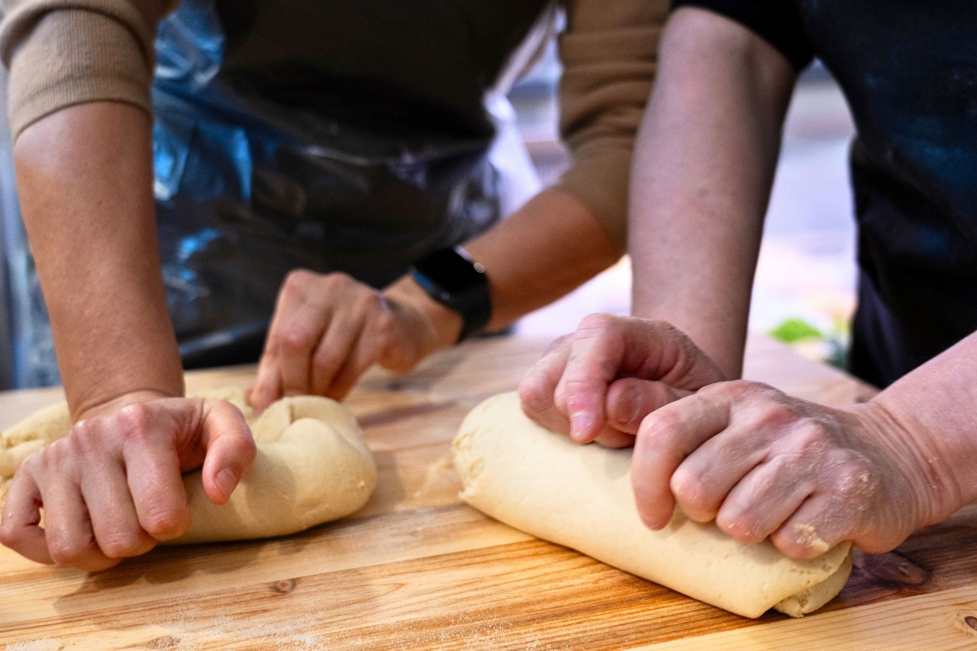 Due persone che lavorano la pasta fresca su un tavolo di legno