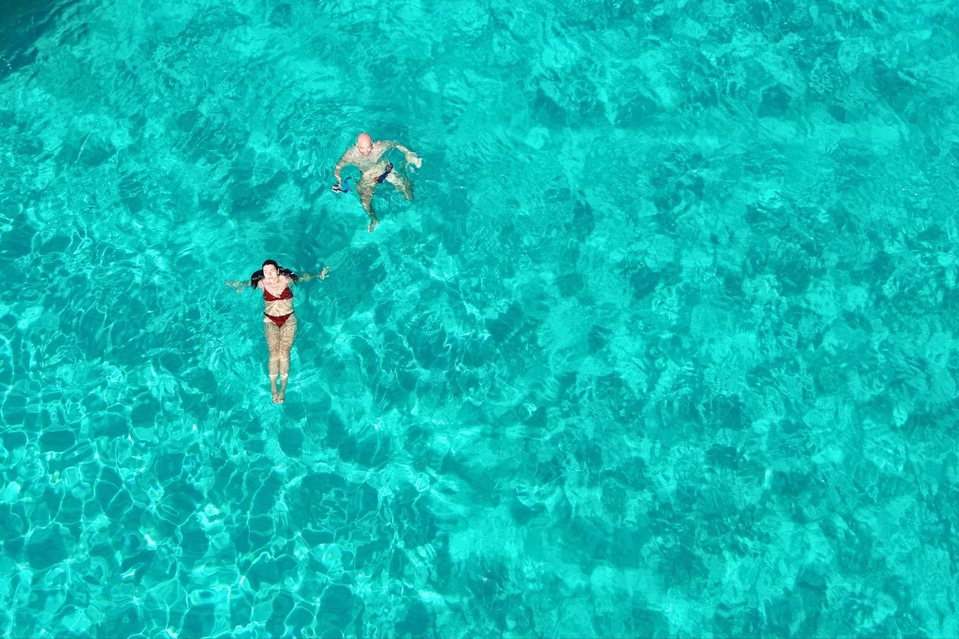 Two people swim in blue water, during a tour to Asinara.
