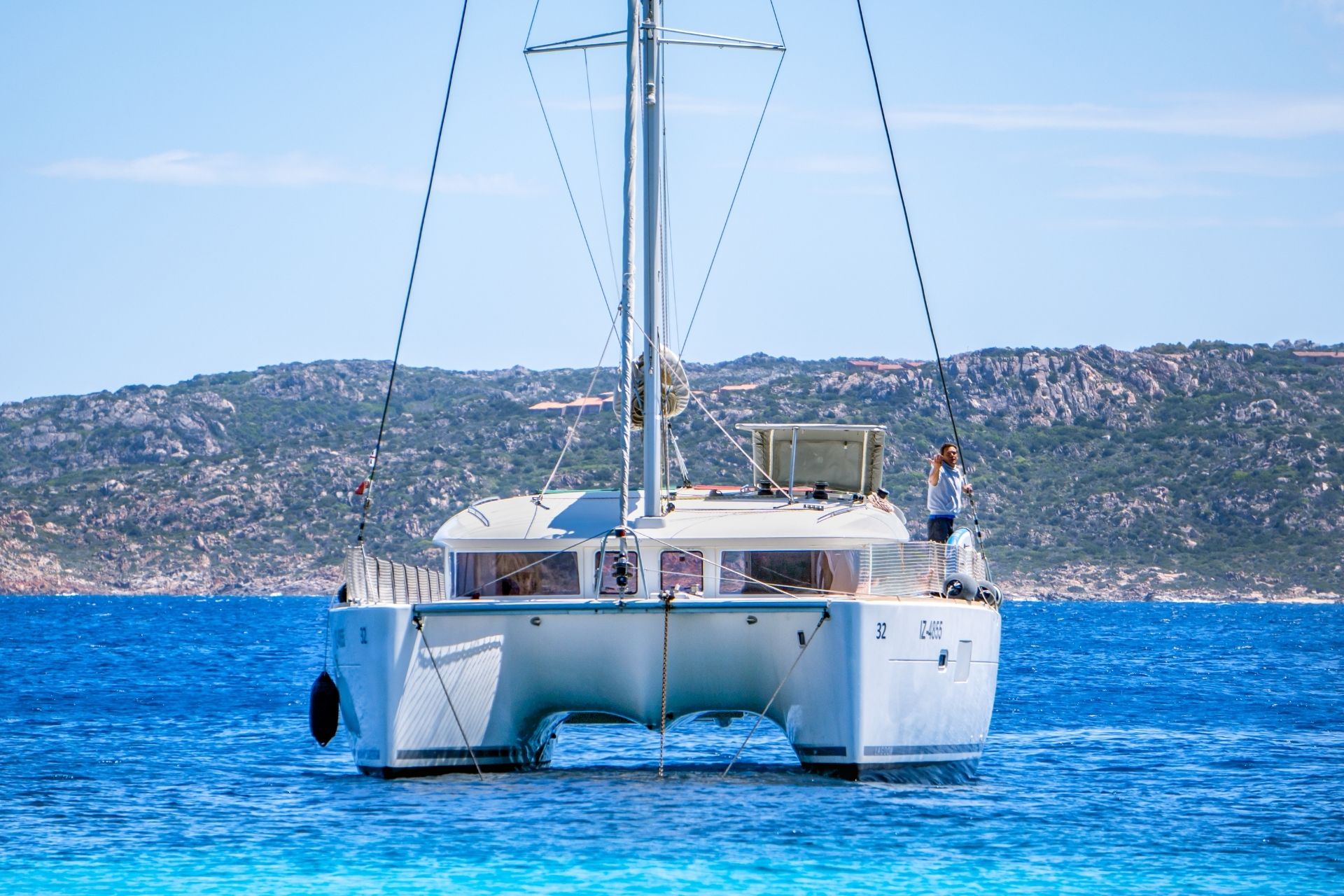 Un bateau traverse un archipel avec des îles en arrière-plan, un homme debout sur la proue.