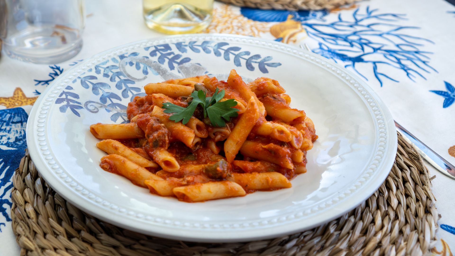 Un plato de pasta sazonado con salsa roja y verduras sobre una mesa
