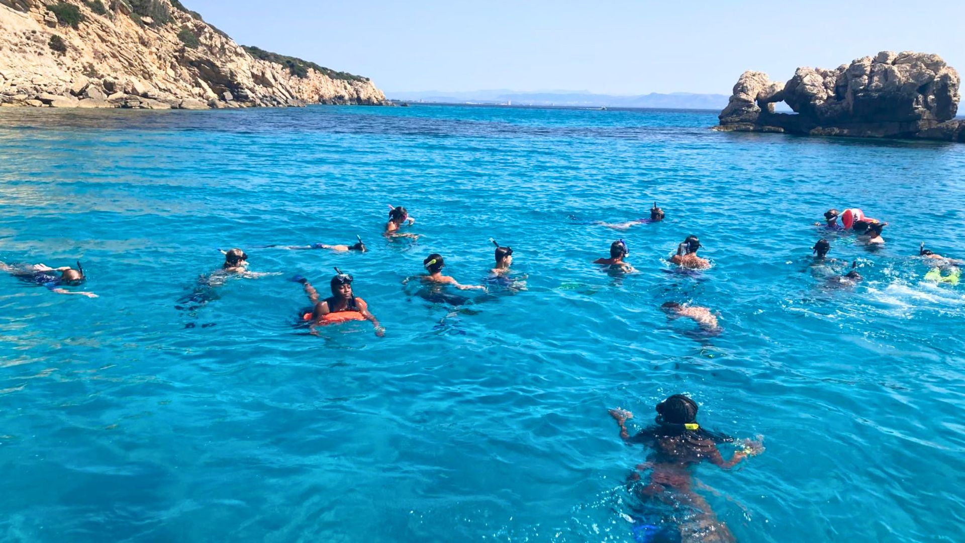 Grupo de personas buceando en aguas cristalinas cerca de una costa rocosa