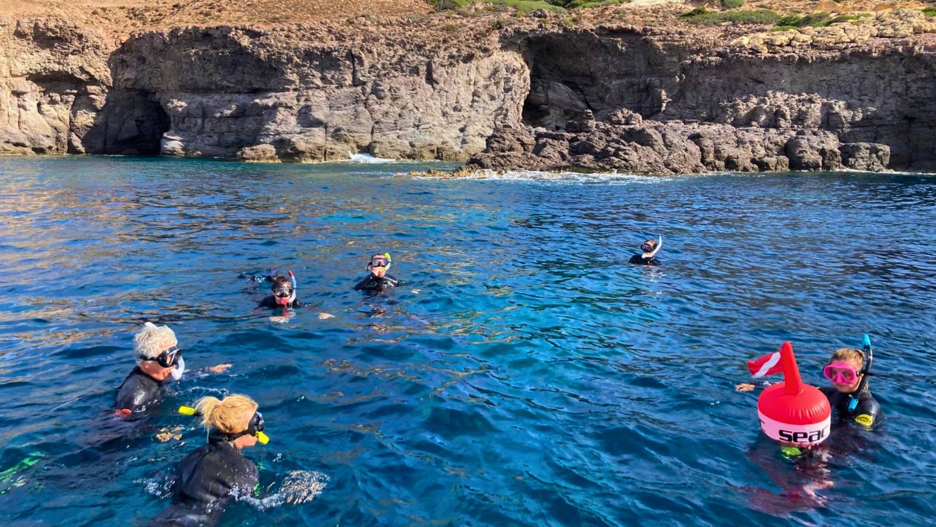 Un grupo de personas en traje de baño y máscaras de snorkel está nadando en el mar