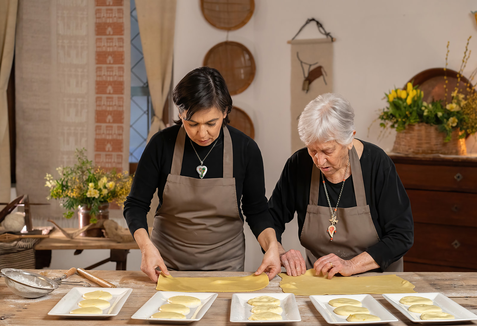 Dos mujeres, probablemente abuelas, preparan postres sardos en una cocina tradicional
