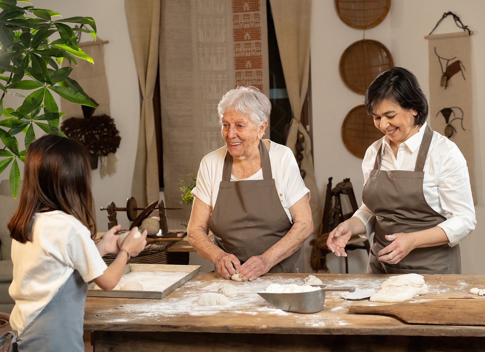 Tres mujeres, dos adultos y un niño, trabajan juntas en una mesa con ingredientes y utensilios de pastelería
