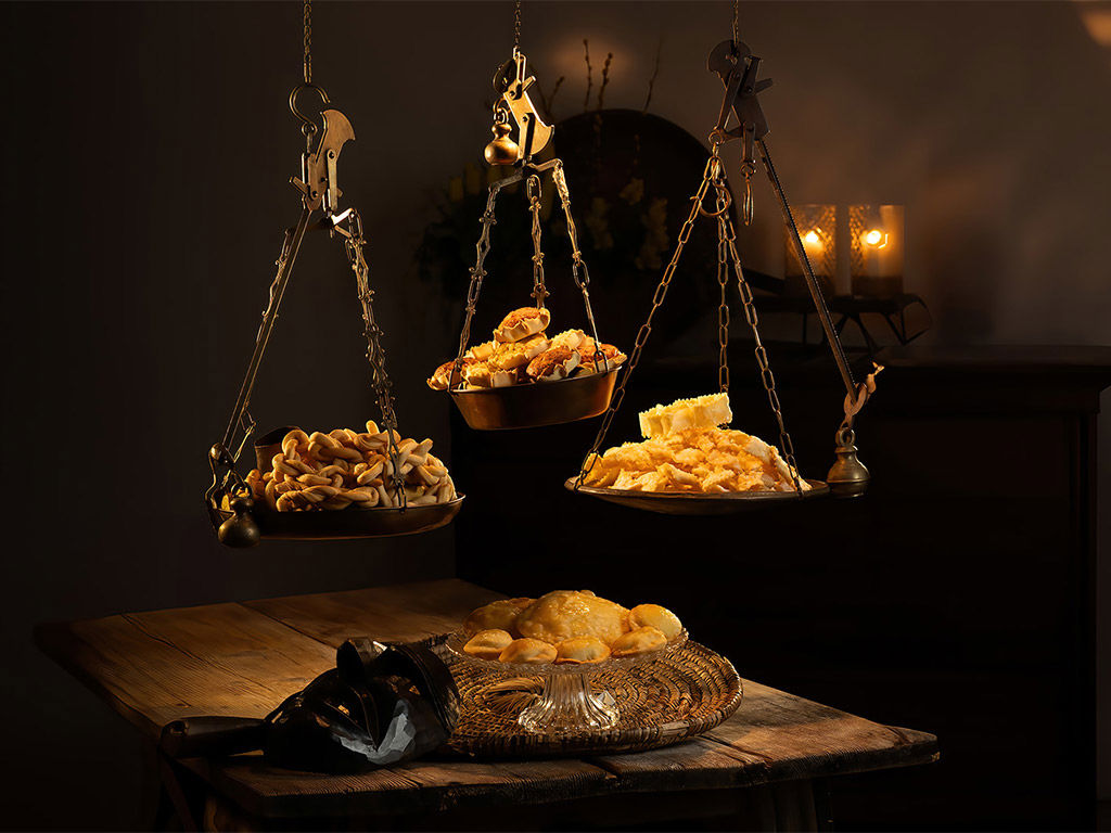 Tres balanzas con platos de postres sardos sobre una mesa