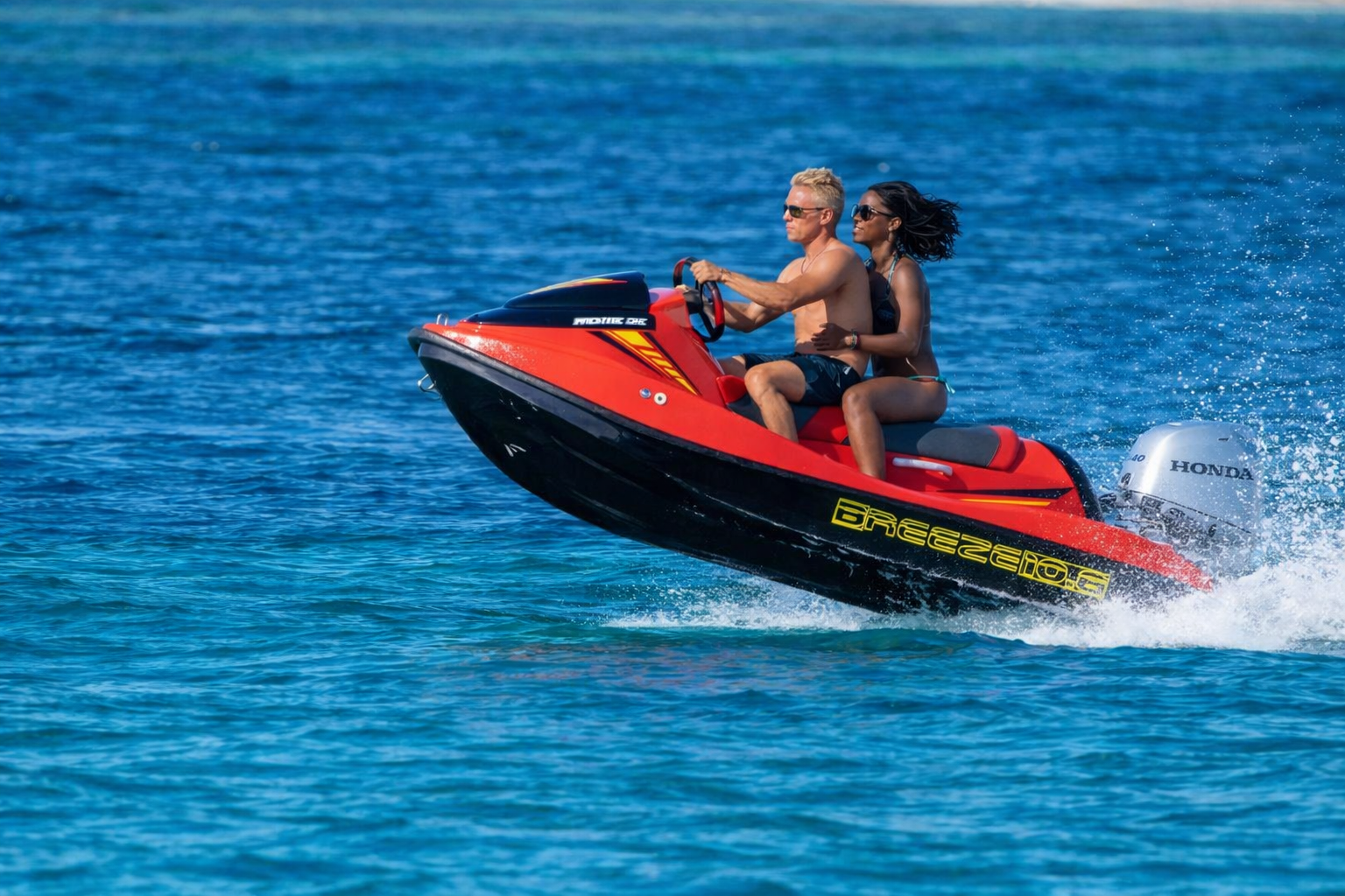 Una coppia in moto d'acqua, con il mare blu sullo sfondo, vive un'esperienza emozionante e avventurosa.