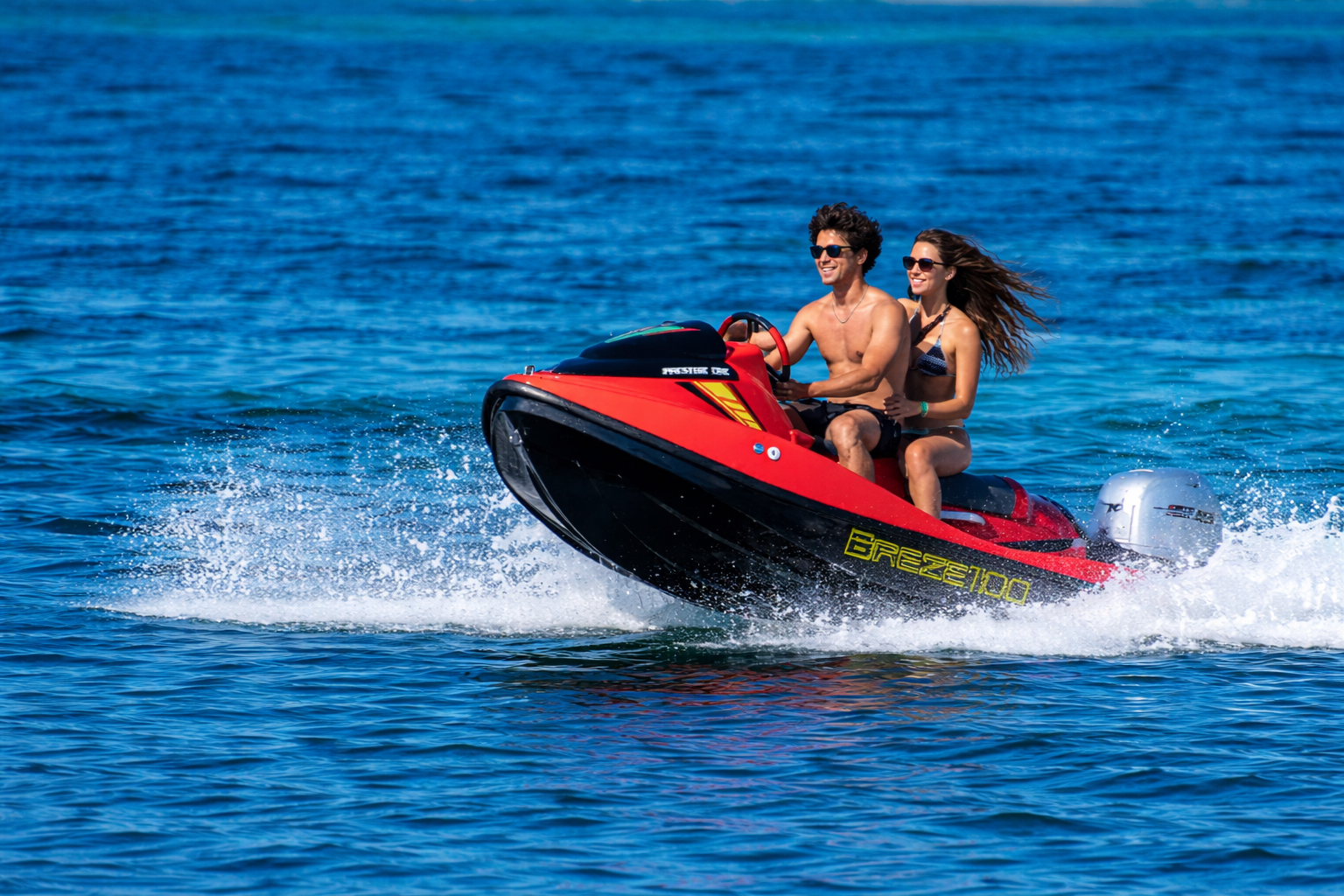 Due persone su una moto d'acqua sfrecciano sul mare di Alghero